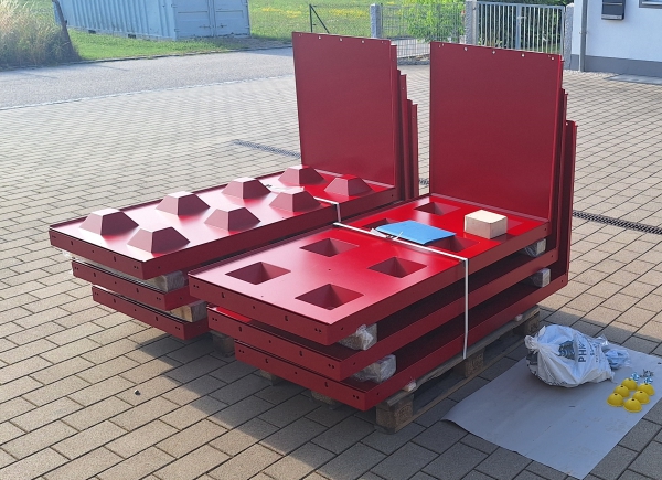 Rote Gießform mit frischen Betonblocksteinen