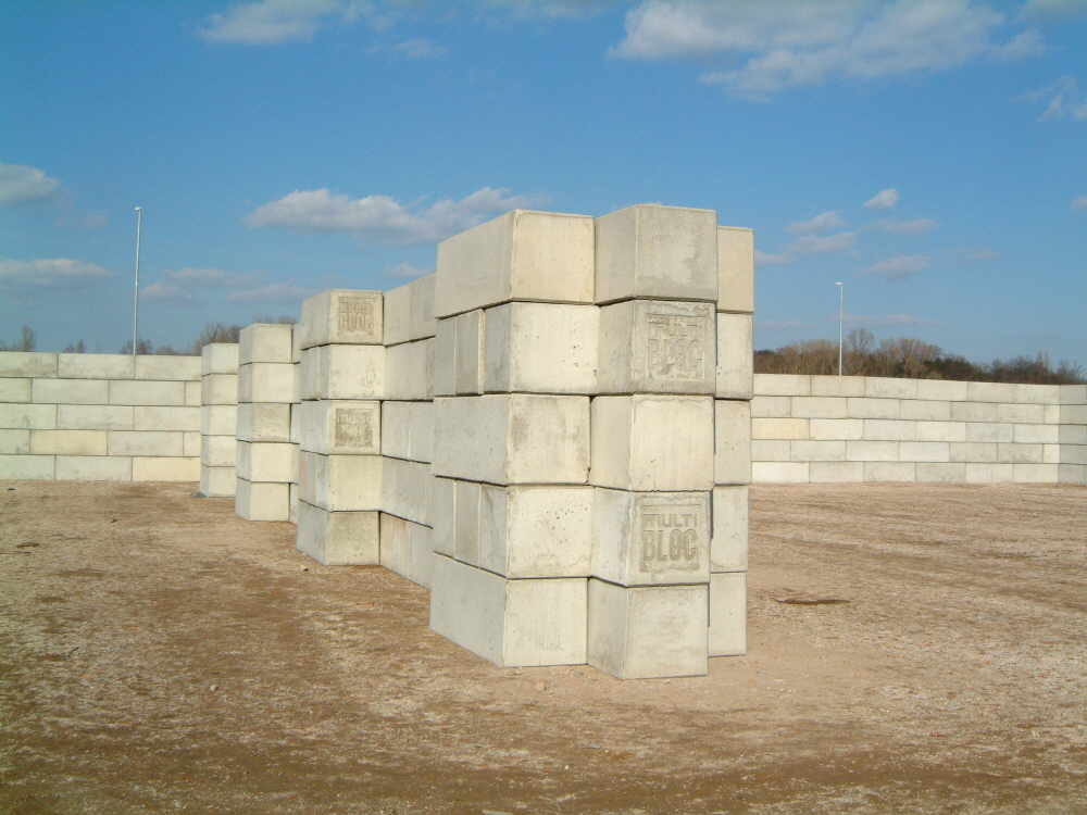 Betonblocksteinwände in unterschiedlicher Höhe, vorn ein schmaler hoher Stapel, hinten eine niedrige lange Wand